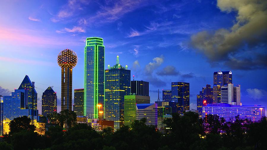Dusk photo of the Dallas skyline, lit by neon lights.